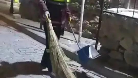 Hem çevreyi temizliyor hem de sokak kedisine süpürgesi ile masaj yapıyor
